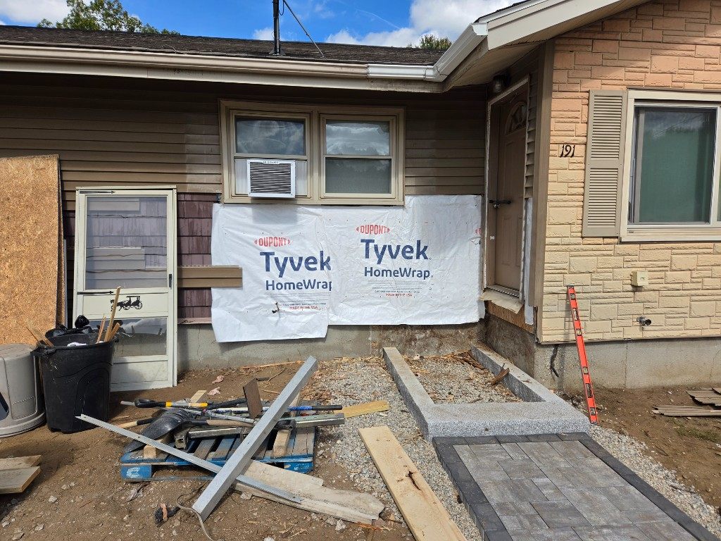 Before — house wrap installed under a window during siding repair in Sutton, MA