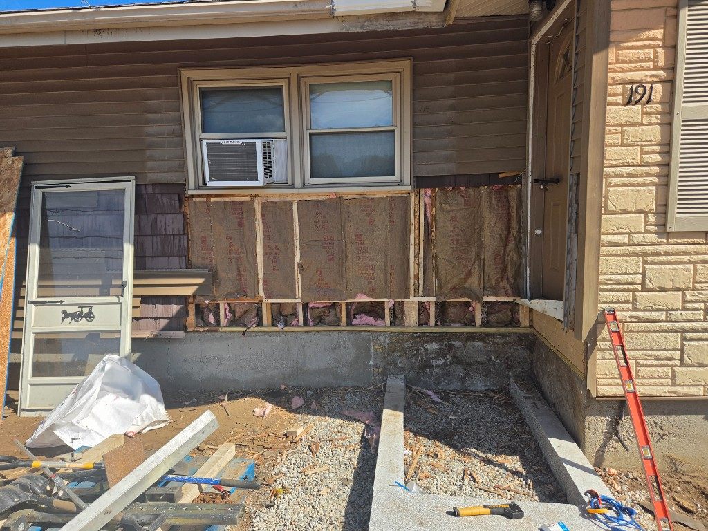 Before — sheathing and insulation exposed under a window during siding repair in Sutton, MA